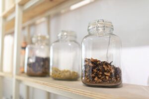 Close-up of glass jars filled with dried herbs on a wooden kitchen shelf.